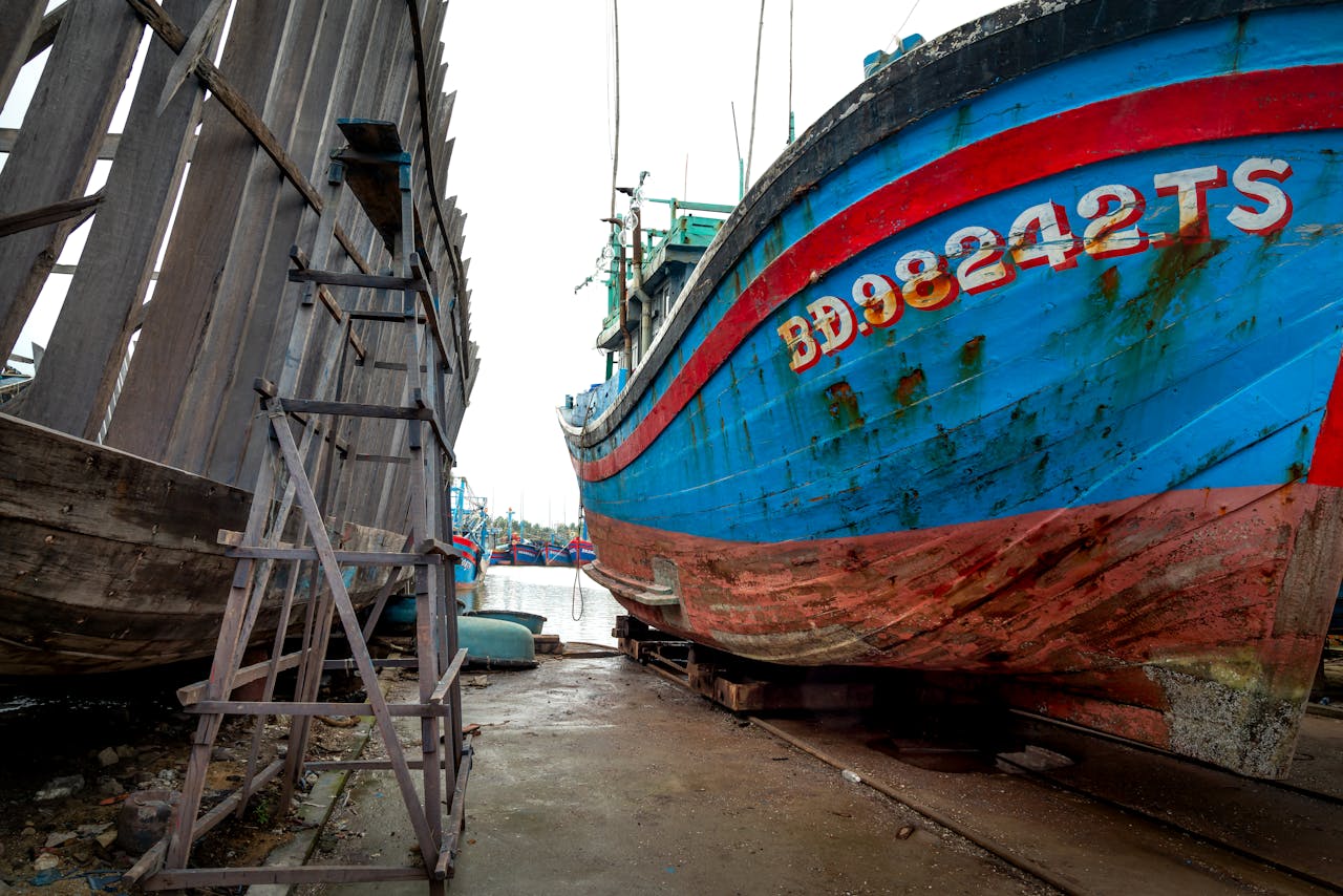 discover Old fishing boats with rusty hulls at a desolate harbor, evoking a sense of history.