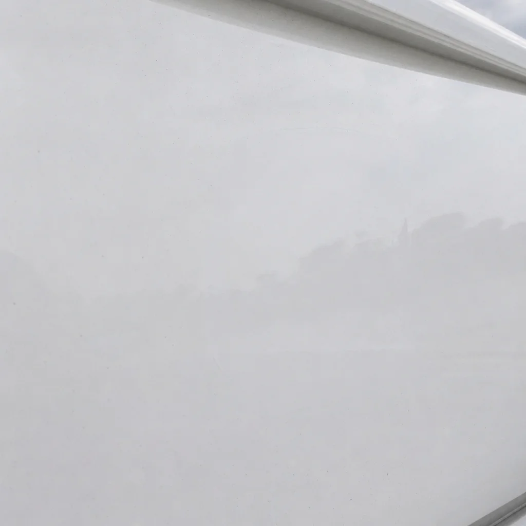 Close-up of white fiberglass boat hull surface with subtle water marks and weathering.